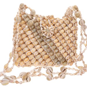 Pode incluir: Uma bolsa de ombro artesanal feita inteiramente de conchas. A bolsa apresenta um corpo retangular com fecho de aba e uma alça feita de conchas menores. As conchas são principalmente creme e bege, com alguns tons verdes.