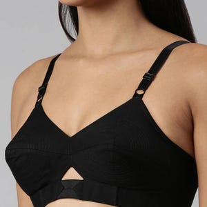 May include: Black bra with adjustable straps and a cut-out design. The bra features a classic silhouette with a V-neckline and a textured pattern on the cups. The straps are adjustable for a comfortable fit.