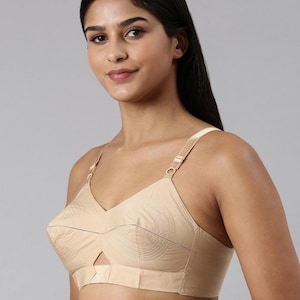 Puede incluir: Sujetador beige con diseño de cuello en V y tirantes ajustables. El sujetador presenta un detalle recortado en el centro y un sutil patrón circular en las copas. El diseño general es simple y elegante.