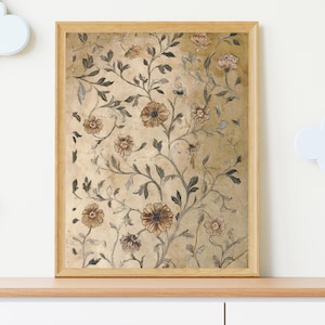 May include: A framed floral print featuring a botanical design with brown and tan flowers and dark green leaves on a gold background. The artwork is encased in a light brown wooden frame, suitable for home decor.