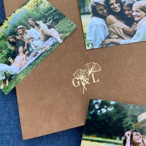 May include: A brown paper envelope with three photographs of women. The envelope has a gold foil design of a ginkgo leaf with the letters G & L.