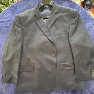 May include: A dark blue blazer with a single-breasted closure and three buttons. The blazer has a classic fit and features a notched lapel, flap pockets, and a welt pocket on the chest.