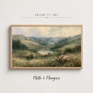 Puede incluir: Una pintura de paisaje en un marco de madera clara que muestra un lago rodeado de colinas verdes y un campo de flores silvestres en primer plano. El texto FRAME TV ART aparece arriba y MOTH & MARGINS aparece debajo del marco.
