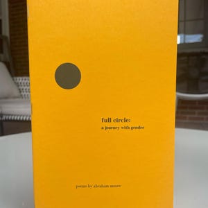 May include: A yellow book with a black circle on the cover. The title is "full circle: a journey with gender" and the author is "abraham moore".
