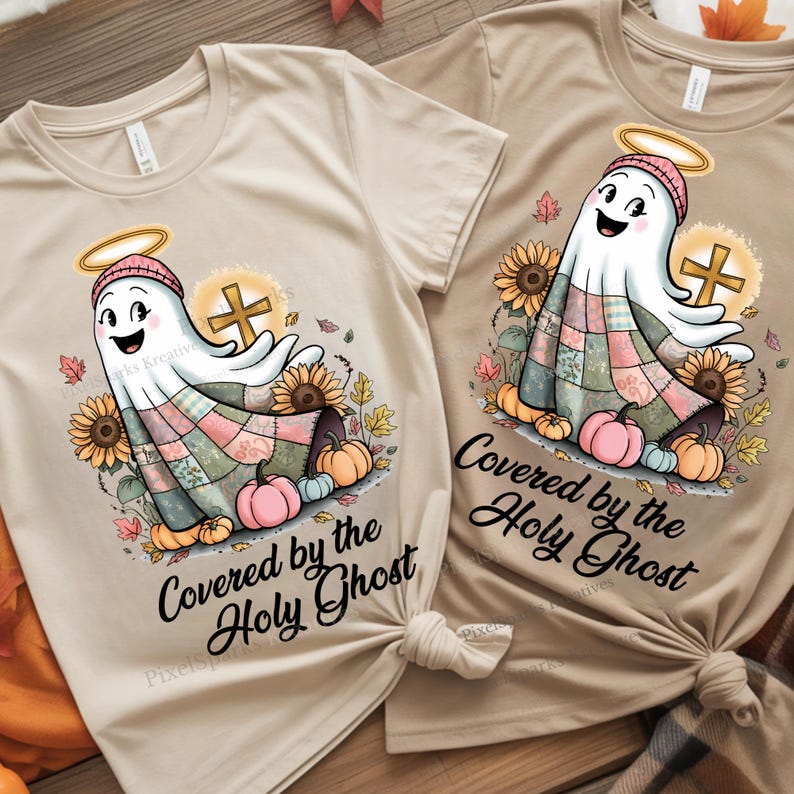 Two t-shirts laid flat side by side, one beige and one cream, both displaying a faith-themed ghost design with soft fall colors and a spiritual quote. The light-toned fabrics highlight the gentle, cozy aesthetic of the artwork — perfect for Christian fall crafting and matching outfits.