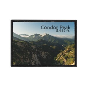 May include: Embroidered patch featuring a scenic mountain landscape with the text "Condor Peak 5,442 ft." The patch has a black border and depicts green hills under a blue sky with clouds.