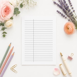 May include: A white rectangular sheet of paper with black horizontal lines and a single vertical margin line. The paper is surrounded by pink and white roses, sprigs of lavender, three colored pencils, a fountain pen, and two gold paper clips.