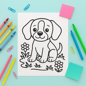 May include: A black and white line drawing of a puppy sitting in grass with flowers. The drawing is on a white sheet of paper, surrounded by colorful crayons, paper clips, and sticky notes on a light blue surface.