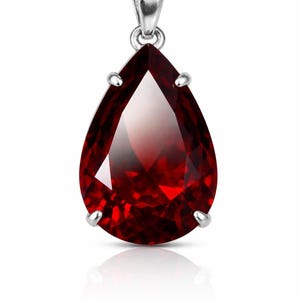 May include: A pear-shaped, deep red faceted gemstone pendant set in a polished silver-toned metal prong setting. The pendant features a teardrop silhouette with a reflective surface and a silver-toned bail at the top for attachment to a chain.