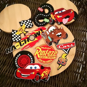 Może przedstawiać: Kolekcja kolorowych naszywek i aplikacji z motywem Aut, w tym Zygzak McQueen, Złomek i różne wzory związane z wyścigami. Naszywki zawierają numer 95, słowa "Cars", "Rust-eze" i "Piston Cup".