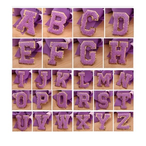 May include: Purple felt letters of the alphabet with gold outlines. Each letter is individually framed and displayed on a white background.