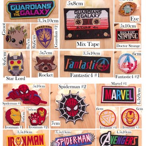 May include: A collection of embroidered fabric patches featuring various Marvel characters and logos, including Guardians of the Galaxy, Doctor Strange, Fantastic 4, Spiderman, Ironman, and Avengers, with visible dimensions in centimeters.