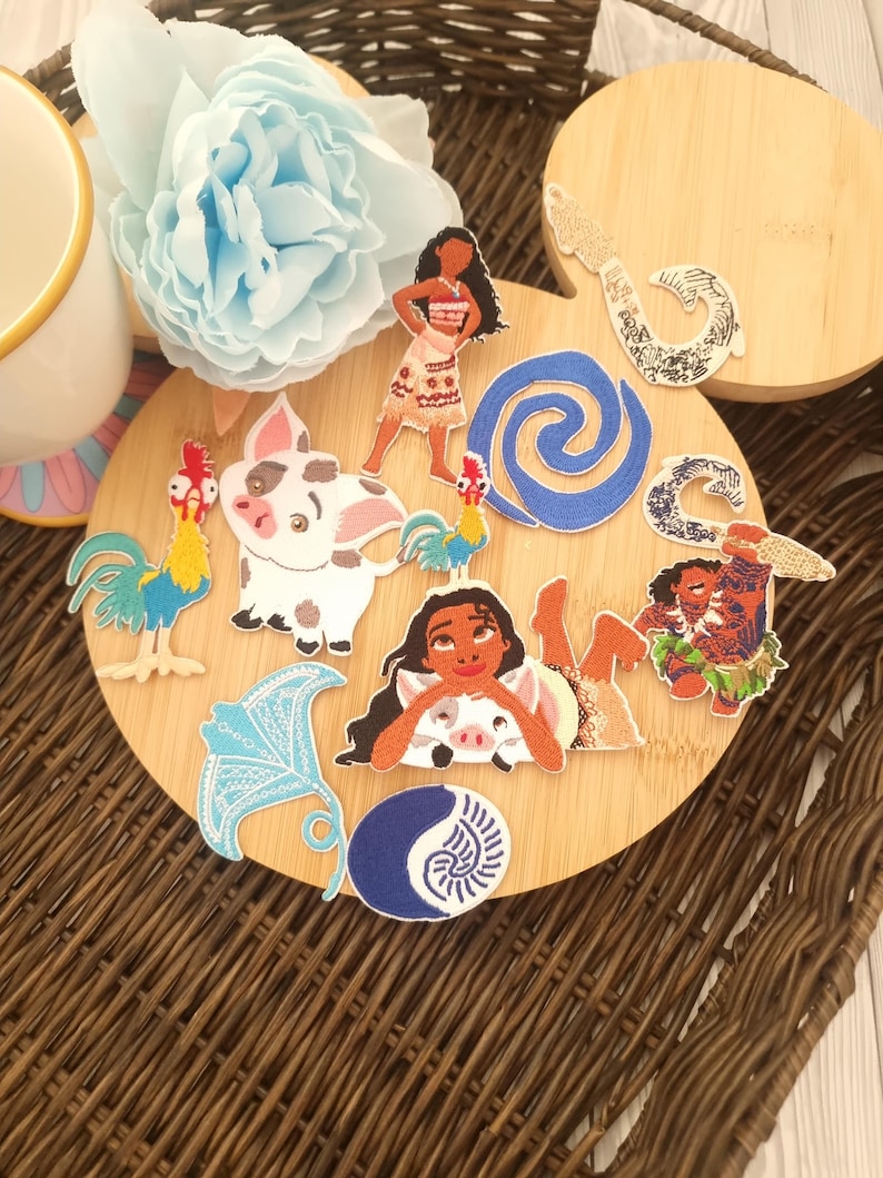 May include: A collection of colorful fabric patches featuring characters and symbols from a popular animated film. The patches include a woman, a pig, a rooster, and other designs, arranged on a wooden surface.