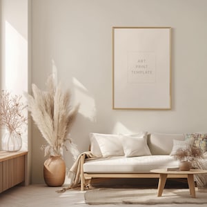 Puede incluir: Un marco de plantilla de impresión artística con el texto "ART PRINT TEMPLATE" cuelga sobre un sofá de color claro con cojines blancos. Un gran jarrón de hierba de la pampa y una pequeña mesa de madera completan la sala de estar de tonos neutros.