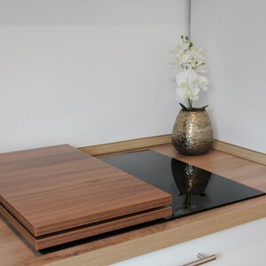 Könnte beinhalten: Eine Arbeitsplatte aus Holz mit einem schwarzen Glas-Induktionskochfeld und einer Holzabdeckung. Eine Vase mit weißen Blumen steht auf der Arbeitsplatte.
