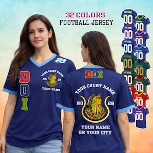 May include: Navy blue football jersey with light blue trim and the text "DOI" in red, yellow, and green. The jersey features a design with a pharaoh and the text "Your Court Name" and "Your Name or Your City". The image also shows multiple color options.