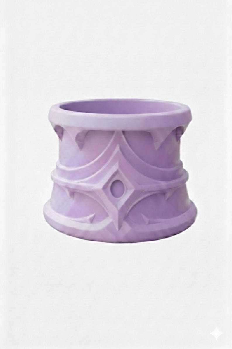 May include: A lavender-colored decorative planter with an ornate design. The planter has a cylindrical shape with a wide opening and a detailed pattern of diamond and curved shapes. The design is repeated around the circumference of the planter.
