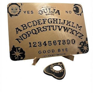 May include: A rectangular gold-colored Ouija board with black lettering, featuring the alphabet, numbers zero through nine, and the words YES, NO, MAYBE, and GOOD BYE. A matching black planchette with a center hole and the text GO AWAY is included.