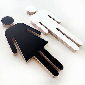 May include: Two layered wooden figures, one black and one white, representing a male and female silhouette. The figures are cut out and layered to create a 3D effect.