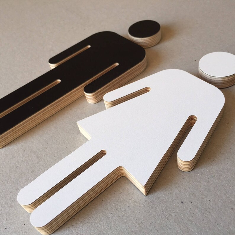 May include: Two layered plywood figures, one black and one white, in the shape of a person. The figures are cut out and have a simple design.
