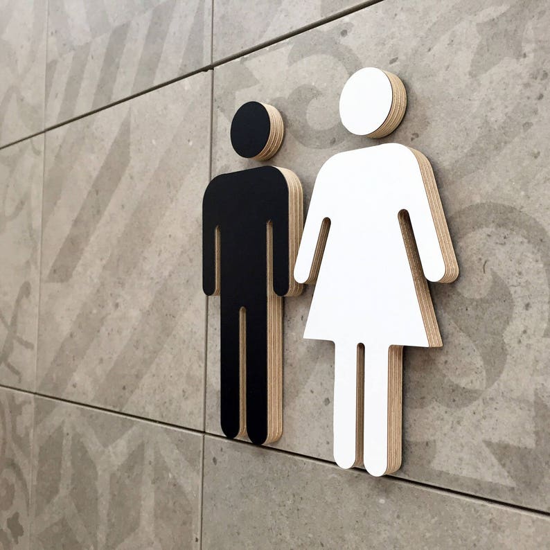 May include: Black and white gender symbol signs on a tiled wall. The male symbol is black and the female symbol is white.