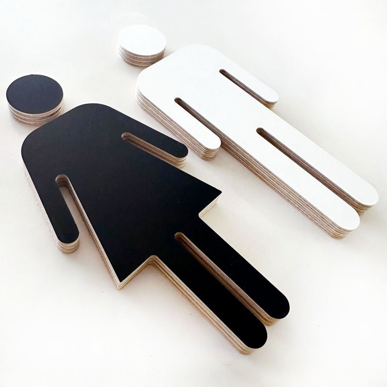 May include: Two layered wooden figures, one black and one white, representing a male and female silhouette. The figures are cut out and layered to create a 3D effect.