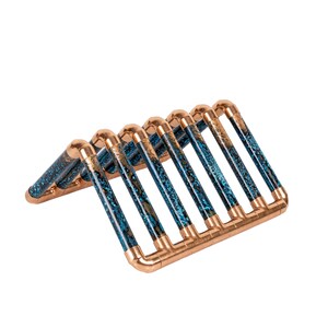 May include: A copper and blue patterned metal wine rack with a triangular shape. The rack is made of copper pipes with a blue and gold epoxy finish.