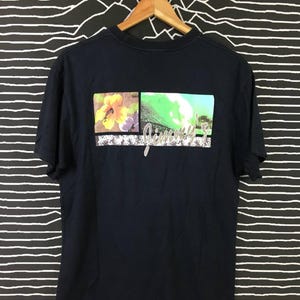 Pode incluir: Uma camiseta azul marinho com uma estampa gráfica de uma flor, uma onda e o texto "Jimmy Z".