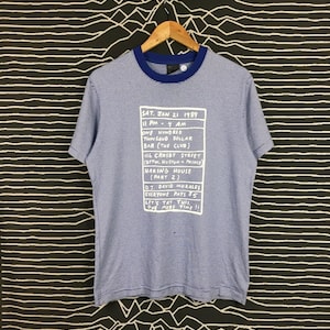 May include: Blue and white striped t-shirt with a white graphic print of a flyer for a party at Haring House on January 21, 1989. The flyer lists the time, location, and DJ David Morales.