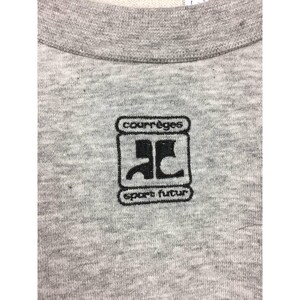 Peut inclure: Gros plan sur un sweat-shirt gris chin&eacute; avec un logo brod&eacute; noir. Le logo comprend le nom de la marque "courr&egrave;ges" au-dessus d'un design stylis&eacute; et les mots "sport futur" en dessous.