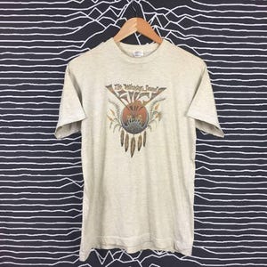 May include: A light gray t-shirt with a vintage graphic of a Native American design and the text "The Wailing Sound".