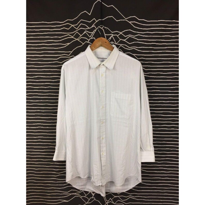 May include: A long-sleeve button-down shirt in a light blue and white pinstripe pattern. The shirt features a classic collar, a single chest pocket on the left side, and a full-length front button placket with matching light-colored buttons.