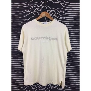 Op de afbeelding: Cr&egrave;mekleurig Courr&egrave;ges Paris T-shirt. De merknaam staat in een zilveren, omlijnde lettertype over de borst. Het shirt heeft korte mouwen en een ronde hals. Het shirt hangt aan een houten hanger.