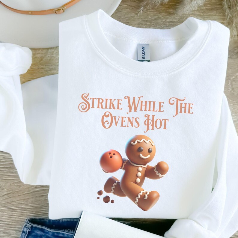 May include: White sweatshirt with a gingerbread man graphic and the text "Strike While The Ovens Hot".