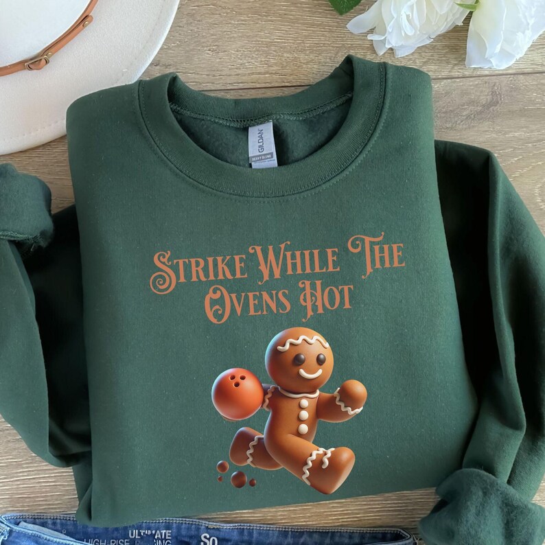 May include: Green sweatshirt with a gingerbread man bowling and the text "Strike While The Ovens Hot" in orange.