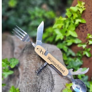 Könnte beinhalten: Ein Multitool mit einem Holzgriff mit einem Bergmotiv und dem Text "Wunschtext". Das Werkzeug beinhaltet eine Gabel, ein Messer, einen Löffel, einen Flaschenöffner und einen Korkenzieher.