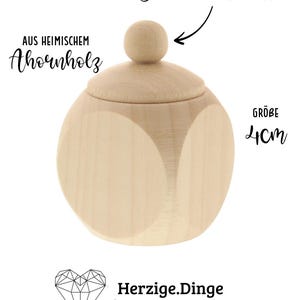 May include: A light-colored wooden container with a rounded shape and a lid. The lid has a small, round knob. The text on the image says "Schraubverschluss", "AUS HEIMISCHEM Ahornholz", "GR&Ouml;BE 4cm", and "Herzige.Dinge Geschenkideen mit Herz".