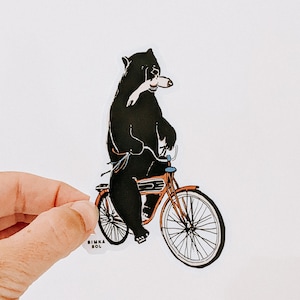Comandeered by Wilderness - 2.62&quot; × 4&quot; Vinyl Sticker, dishwasher safe, bear on bike, bike ride animal, dark humor sticker, bear riding bike