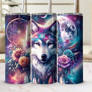Pode incluir: Três copos de aço inoxidável com um design colorido que apresenta uma cabeça de lobo, flores e um apanhador de sonhos. A pelagem do lobo é uma mistura de roxo, azul e branco, e as flores são rosa, roxas e azuis. O fundo é azul escuro com estrelas e uma lua crescente.