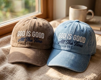 以下が含まれることがあります： ブラウンとライトブルーの野球帽が2つ。どちらもフロントパネルに「GOD IS GOOD All The Time」という白とダークブルーの刺繍が施されています。各キャップには、構造化されたクラウン、カーブしたつば、ステッチされたアイレットが付いています。