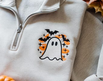 Könnte beinhalten: Hellgraues Sweatshirt mit Viertelreißverschluss und Halloween-Stickerei. Das Design zeigt einen weißen Geist, orangefarbene Kürbisse, schwarze Fledermäuse und orangefarbene Sterne. Das Sweatshirt hat einen silbernen Reißverschluss.