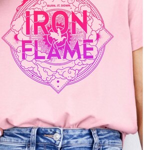 May include: Pink t-shirt with a graphic design of a circle with the words "BURN IT DOWN" and "IRON FLAME" in a pink and purple gradient. The back of the shirt features a pink and purple gradient dragon.