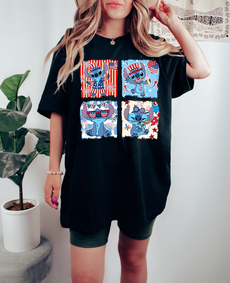 May include: Black t-shirt with a four-panel graphic of a blue cartoon character in patriotic outfits. Each panel shows the character with American flag elements, such as a hat and sunglasses. The design is set against red, white, and blue backgrounds.