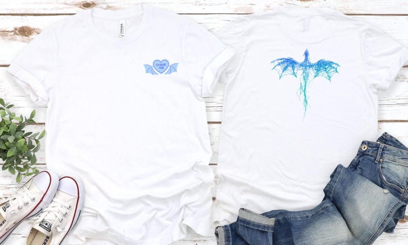 K&ouml;nnte beinhalten: Zwei wei&szlig;e T-Shirts mit blauen Grafiken. Ein Shirt zeigt ein blaues Herz mit Fl&uuml;geln und dem Text "Forever Mine". Das andere Shirt zeigt einen blauen Drachen mit Fl&uuml;geln.