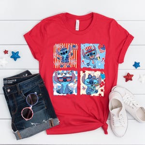 May include: A red t-shirt with four squares depicting the cartoon character Stitch in patriotic designs. The shirt is styled with denim shorts, sunglasses, and white trainers. Decorative stars are scattered around the items.