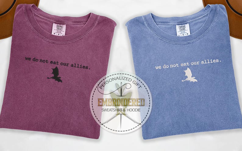 May include: Two t-shirts with the text "we do not eat our allies." and a dragon silhouette. The t-shirts are in burgundy and blue.