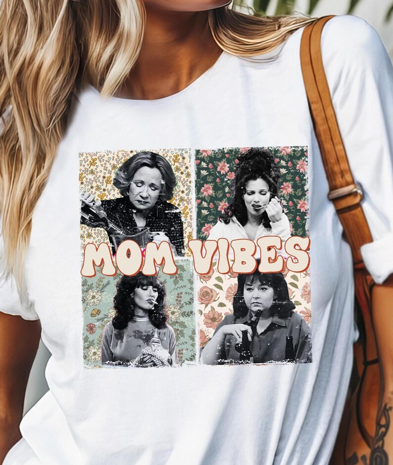Pu&ograve; includere: Maglietta bianca con una grafica in stile vintage che presenta quattro donne con sfondi floreali e il testo "MOM VIBES".