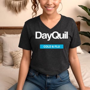 May include: A dark gray V-neck t-shirt with the text "DayQuil COLD & FLU" printed in white.