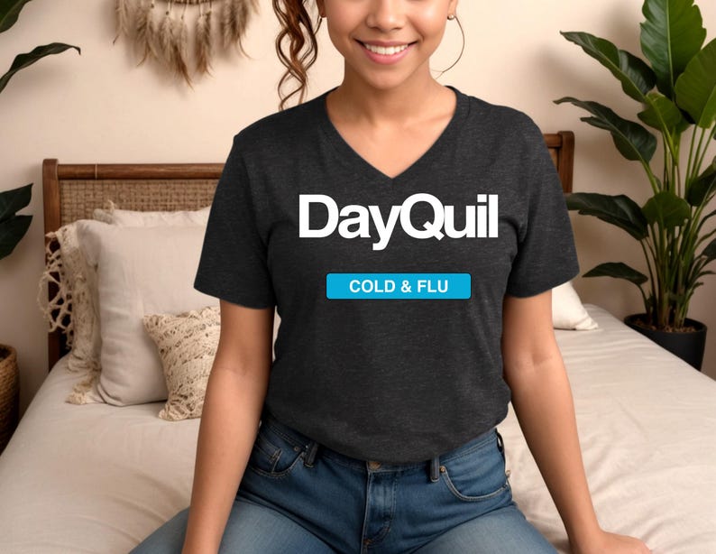 May include: A dark gray V-neck t-shirt with the text "DayQuil COLD & FLU" printed in white.