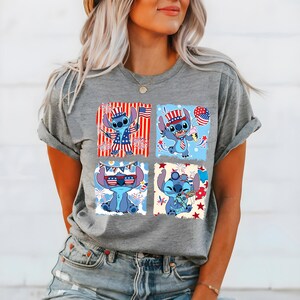 May include: A grey t-shirt with a four-panel design of the character Stitch in patriotic attire. Each panel shows Stitch with American flag-themed accessories, including a hat, sunglasses, and holding a flag and ice cream.